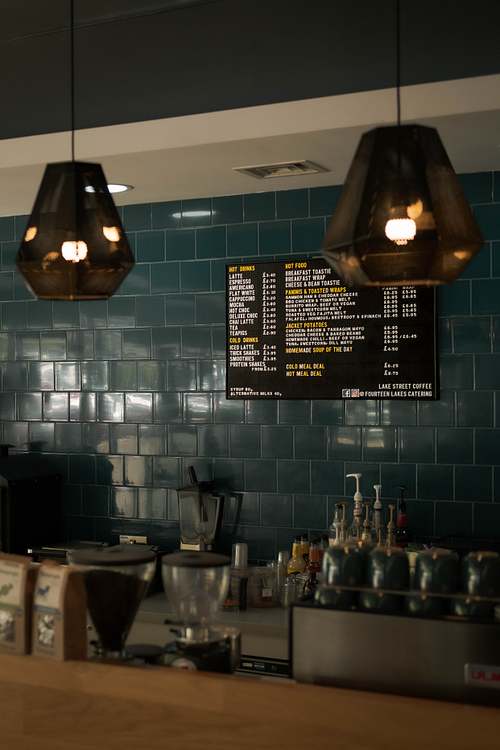 Café counter with pendant lights, menu boards, and cups inside an independent coffee shop