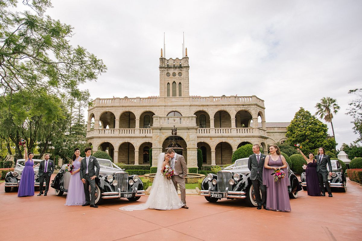 Bridal party with their classic bridal cars in front Curzon Hall.