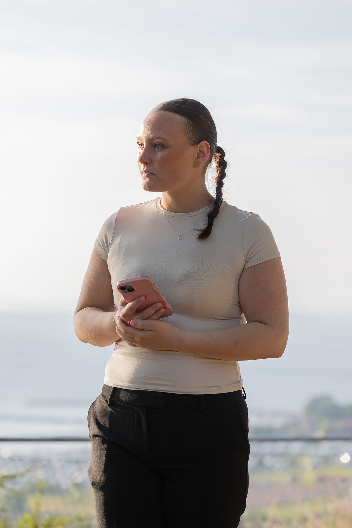 Kvinna i mjukt kv&auml;llsljus med mobil, redaktionellt milj&ouml;portr&auml;tt i Stockholm