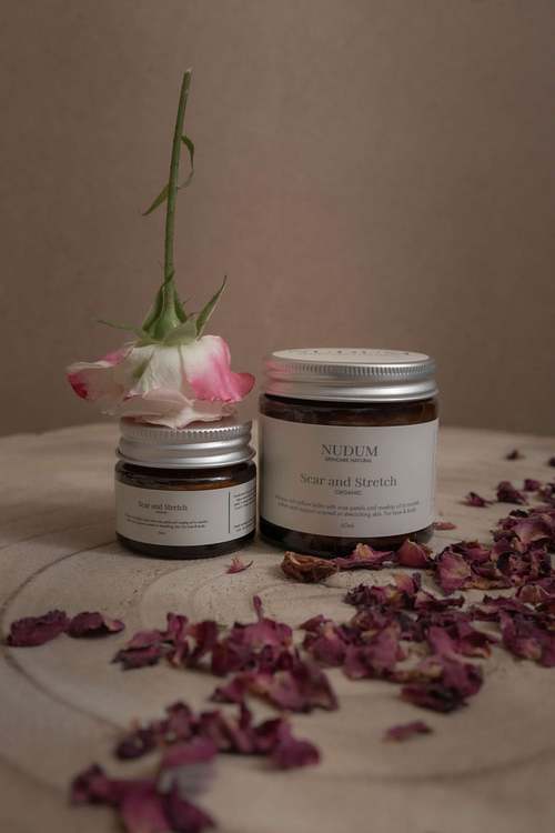 Product jars styled with dried botanicals on a neutral surface