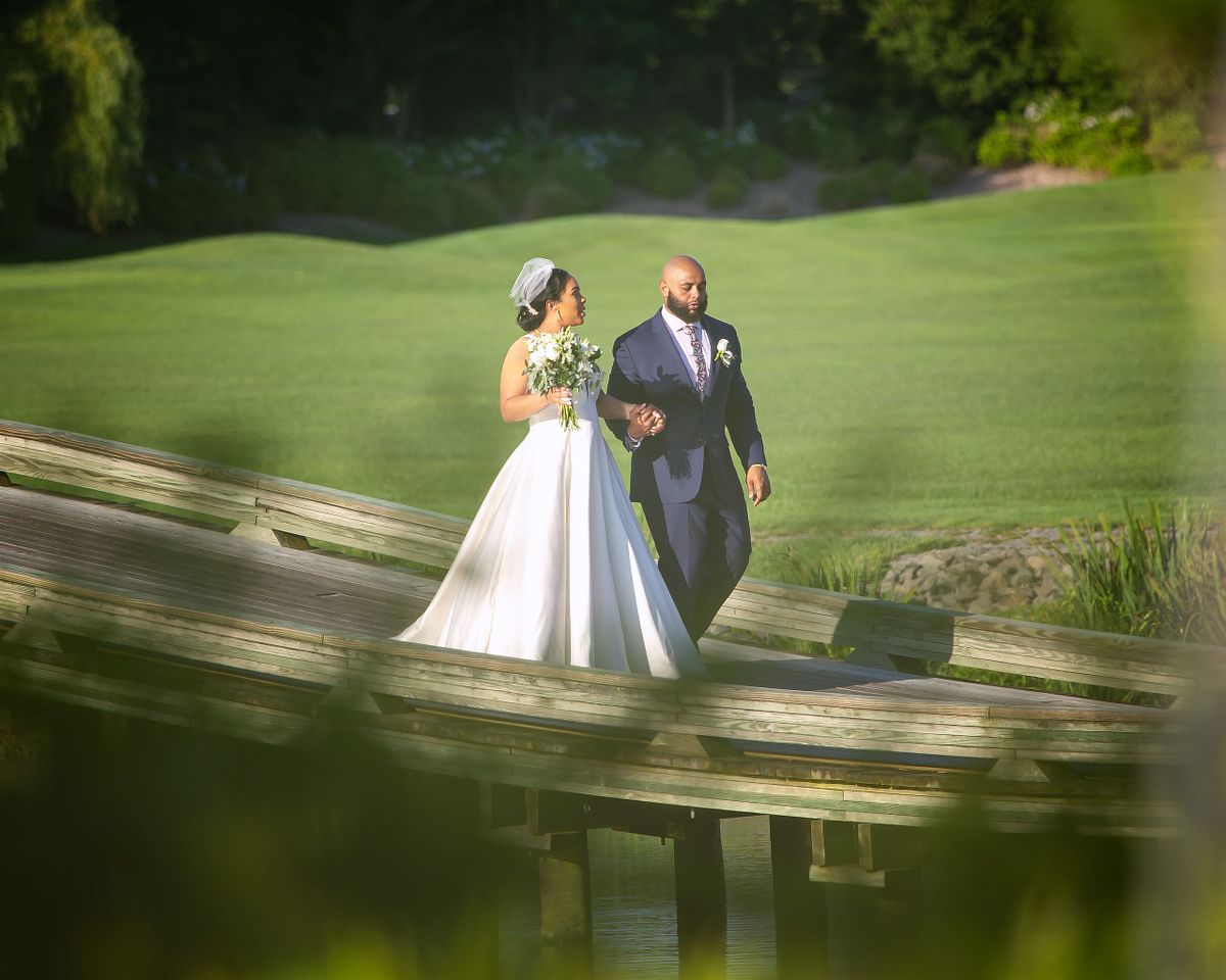 bride and groom walking across the bridge at award winning wedding venue