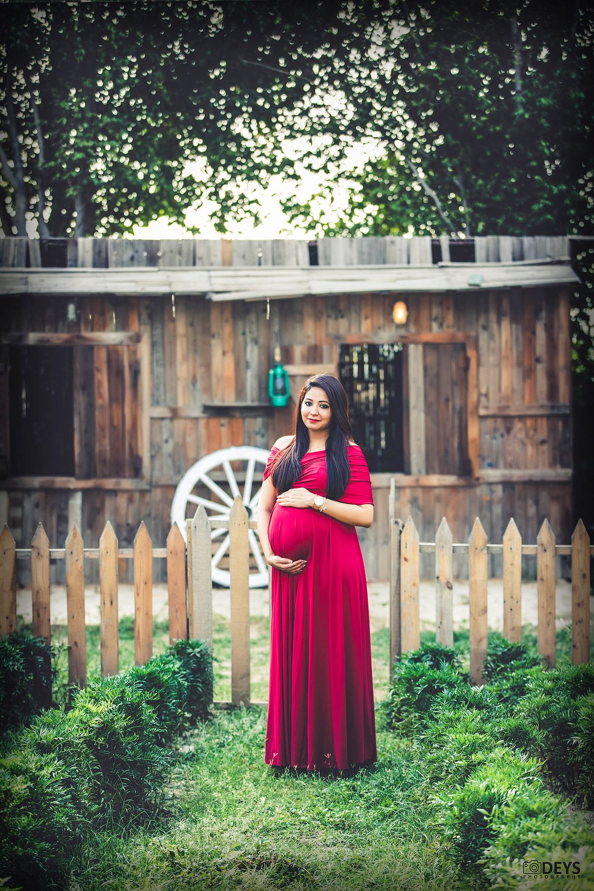 Red gown maternity photography at theme studio in Delhi