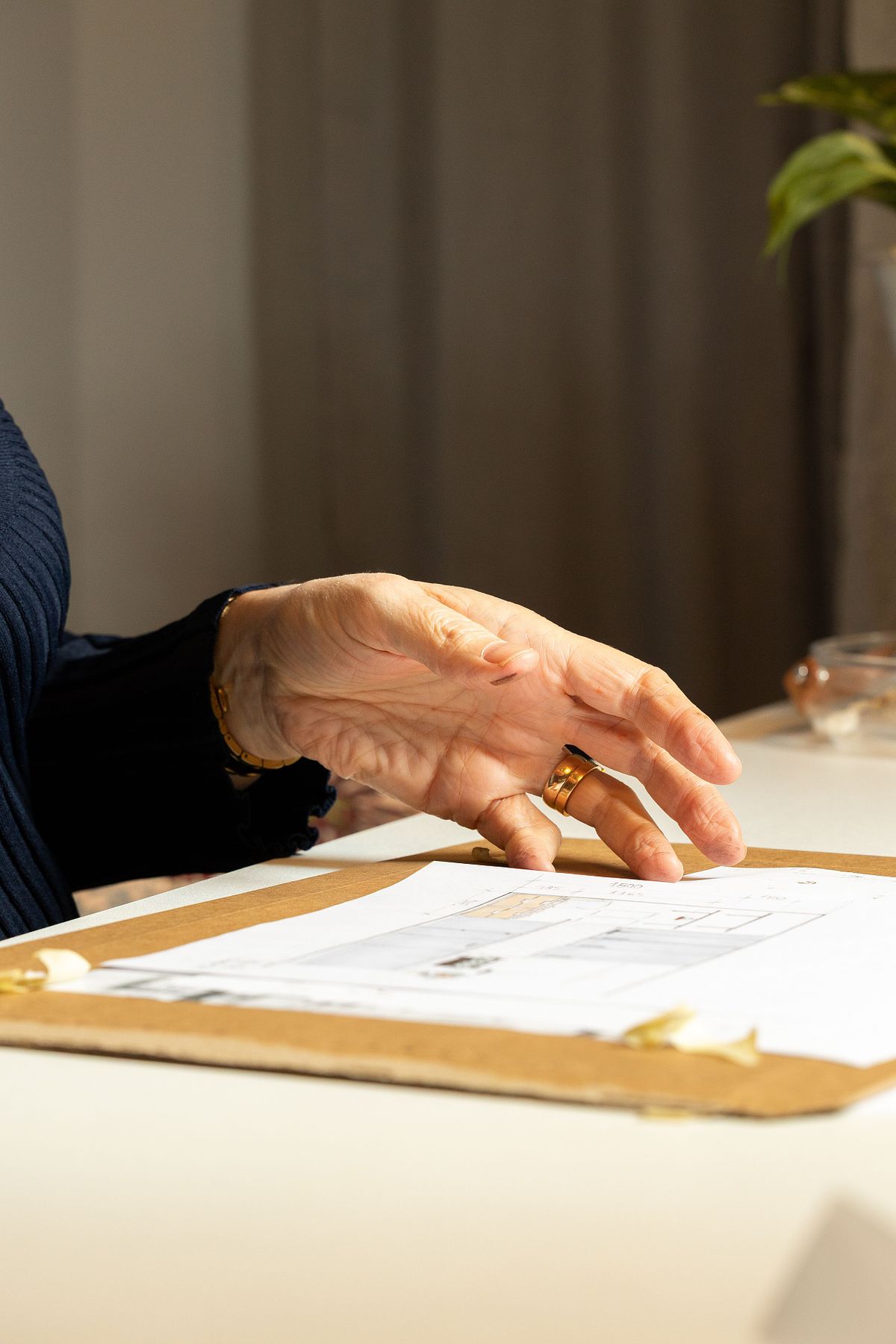 Hand som gestikulerar &ouml;ver ritning p&aring; bord, som del av planering och inredningsdesign.