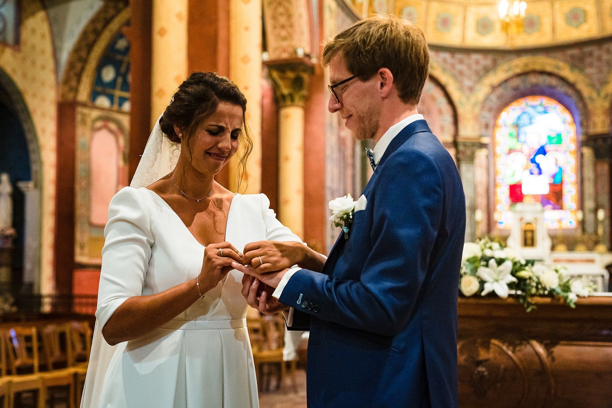 Mari&eacute;e qui a du mal &agrave; passer la bague au doigt &agrave; son mari &agrave; l'&eacute;glise durant la c&eacute;r&eacute;monie captur&eacute; par S&eacute;bastien CLAVEL photographe de Mariage &agrave; Lyon et Gen&egrave;ve