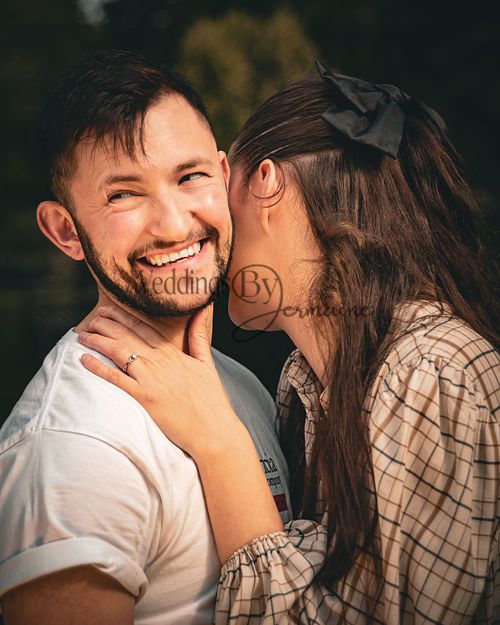 Alex and Shelby in a sweet embrace during their engagement shoot, with the groom smiling and looking at the camera while the bride-to-be shyly looks away, sharing an inside joke, captured by Weddings by Jermaine