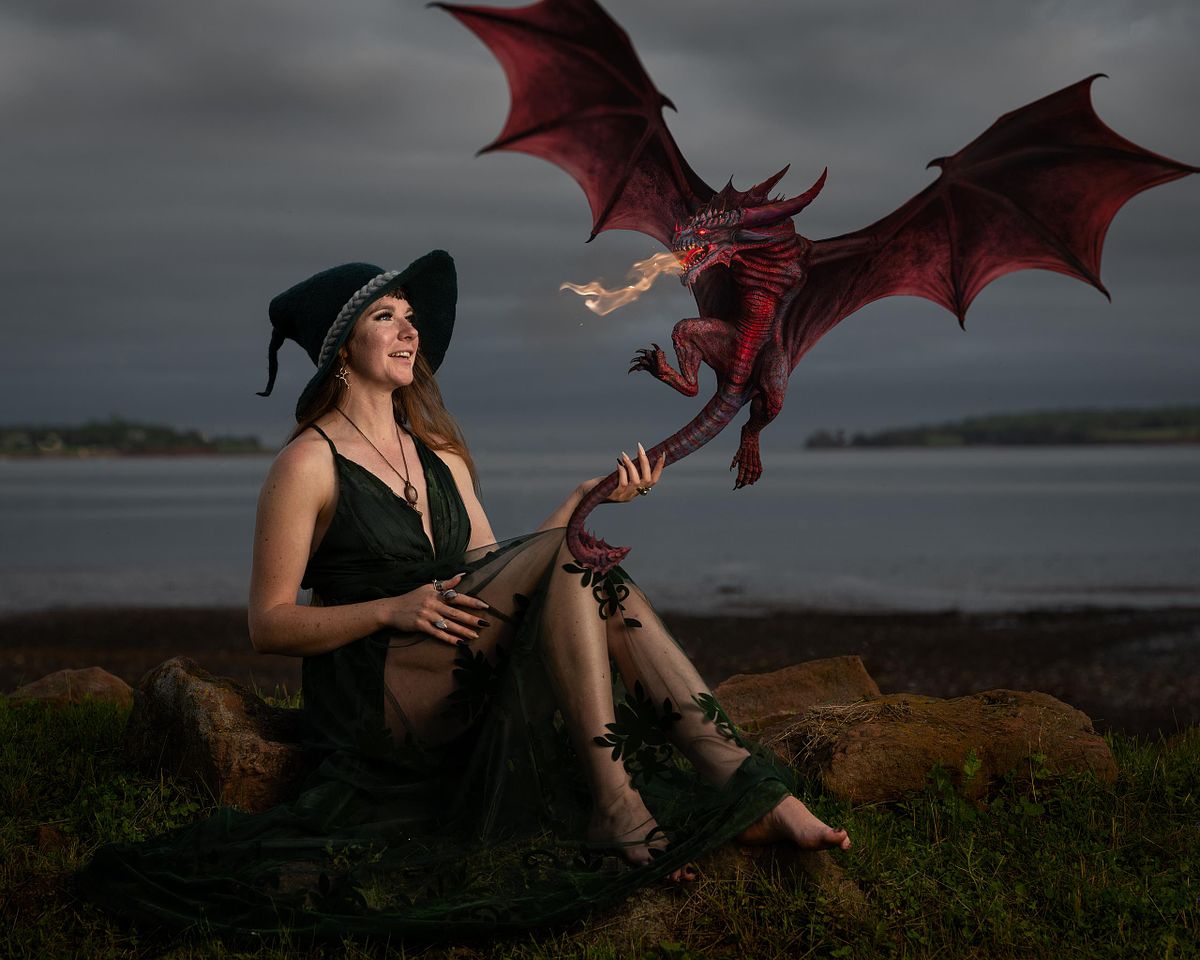 A witch sitting on rocks by the ocean delighted by her dragon flying in.