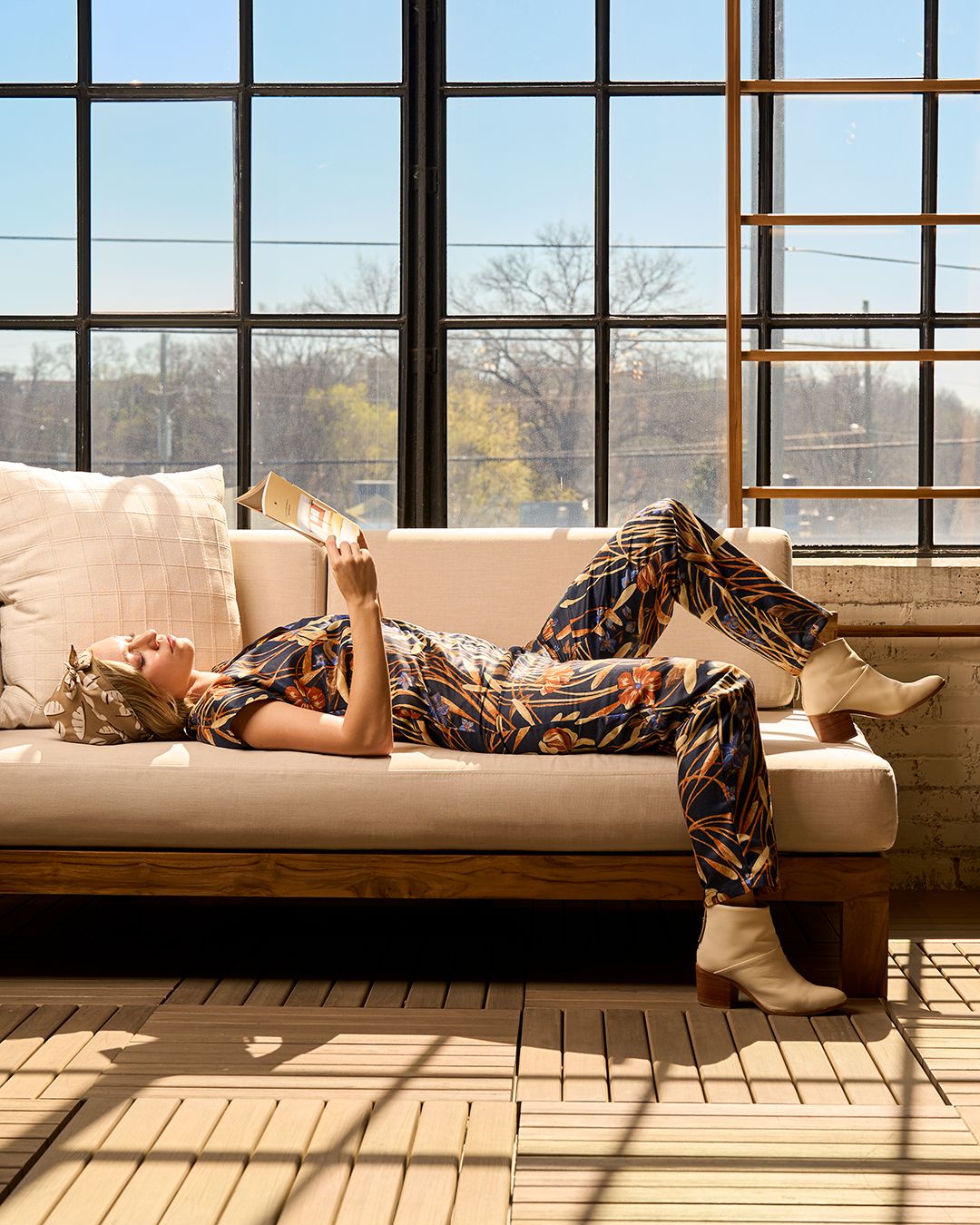 Female model lounging back on a couch wearing a custom bodysuit designed by Cybelle Elena