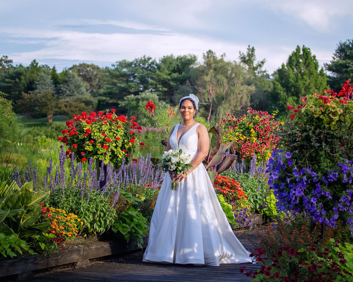 bride surrounded by flowers standing on the bridge on the golf course at bay