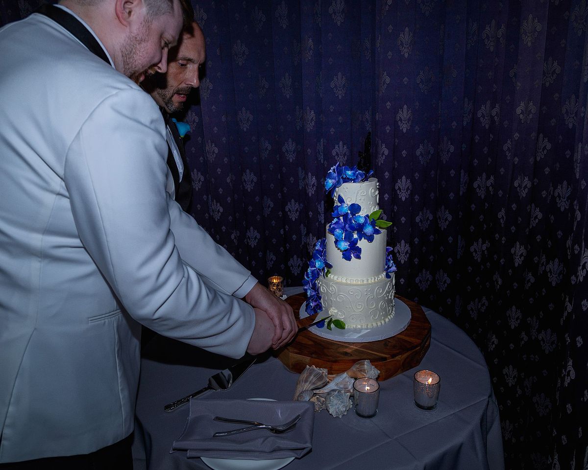 gay couple cutting cake documented with flash photography in sussex county, de