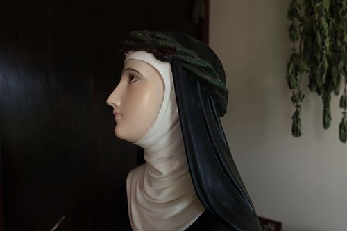Very pale face of St. Catherine statue in need of repainting