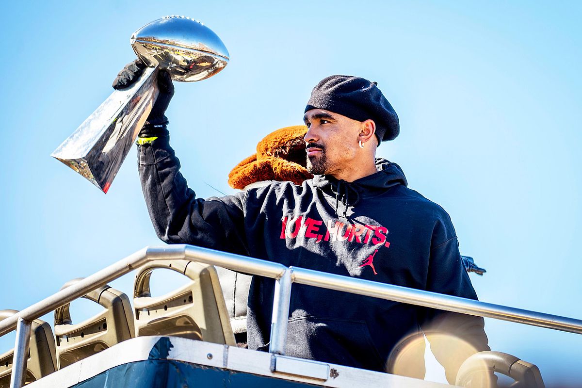 Editorial event photography of Philadelphia Eagles quarterback Jalen Hurts raising the Vince Lombardi Trophy during the city’s championship parade, symbolizing leadership, pride, and legacy.