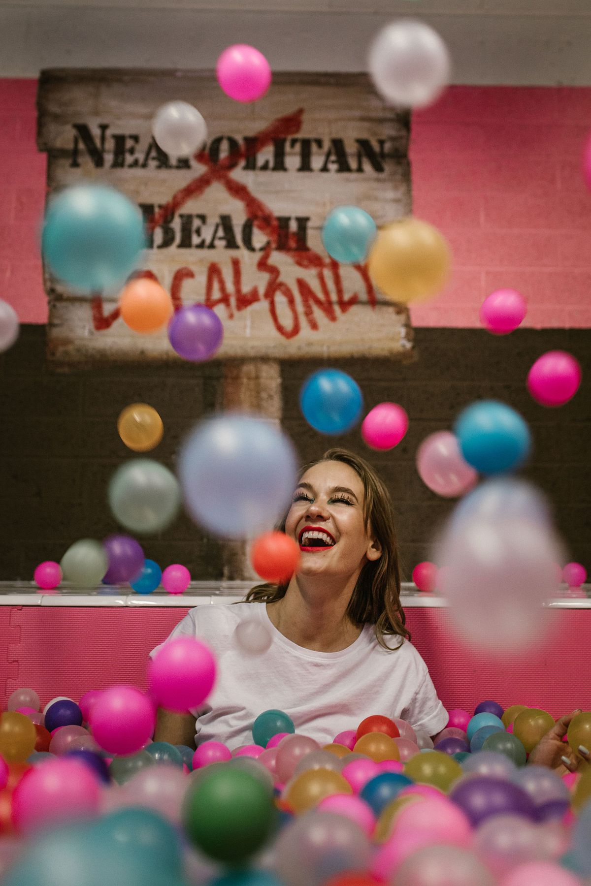 Fun, colorful boudoir photo with woman immersed in a playful adult-sized ball pit.