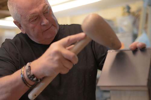 Person sanding and shaping wood while building a handmade bee and bug house