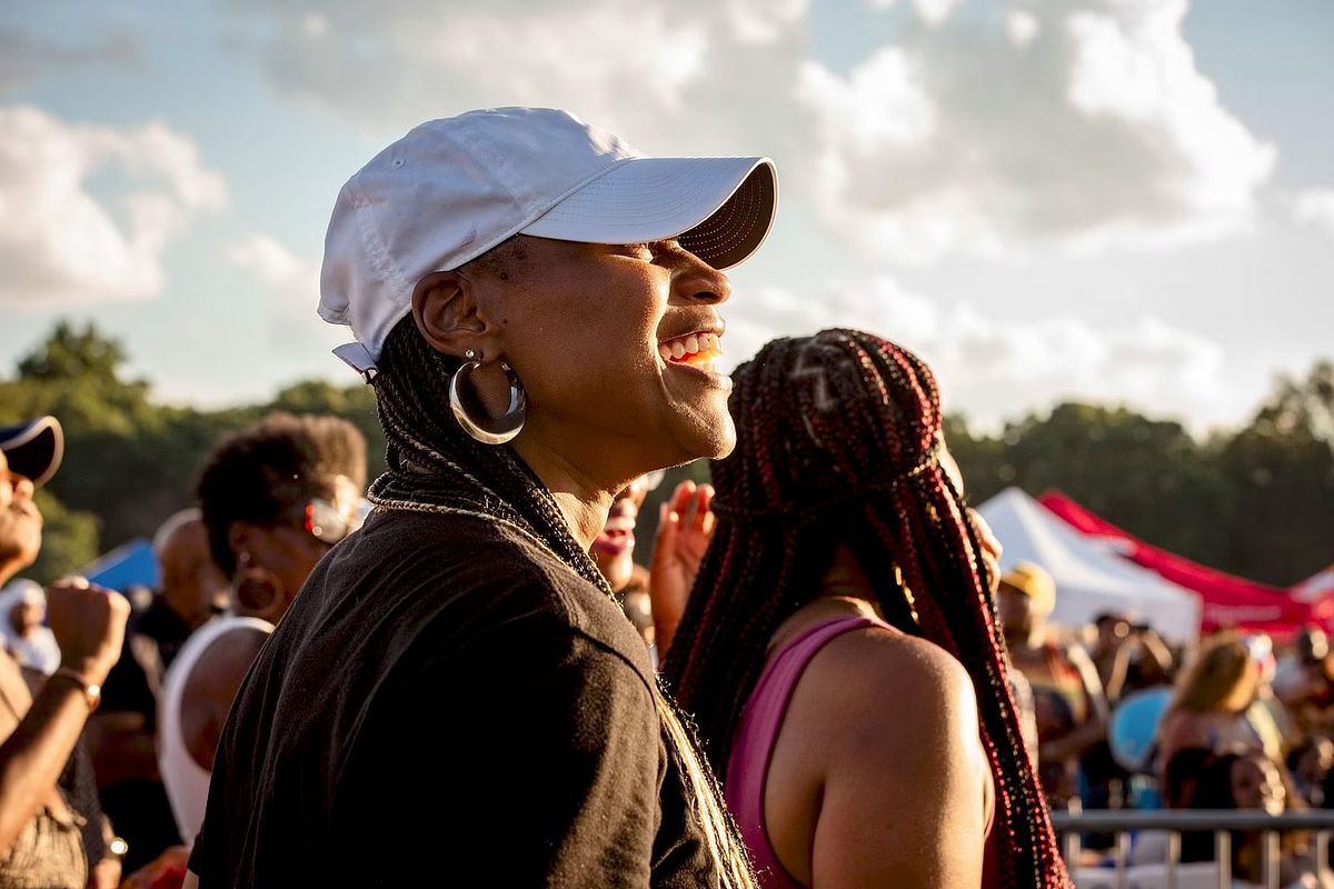 Documentary-style event photography of a woman smiling in the crowd during a Philadelphia summer festival, capturing authentic emotion, community energy, and cultural vibrance.