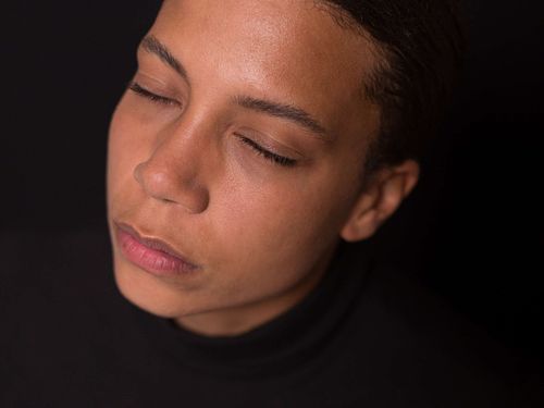 A headshot of a woman in a black turtleneck with her eyes closed.