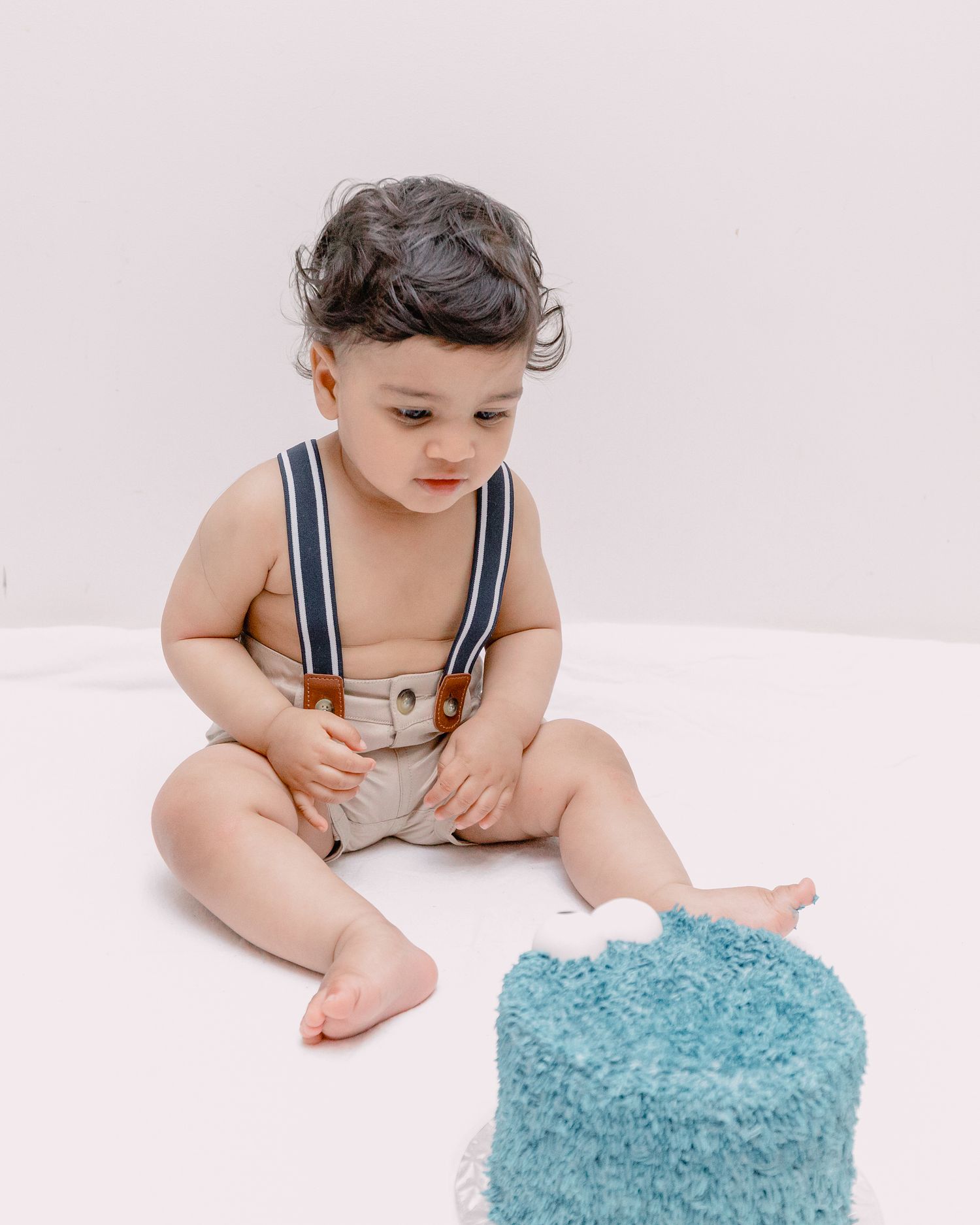 Basel photographer capturing a cute baby looking at a smash cake for the very first time with curiosity and intrigue