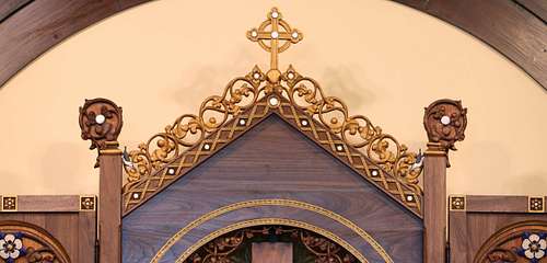 Detail photo of the upper part of the altarpiece showing the crockets, finials, cross, flowers, and nuthatches