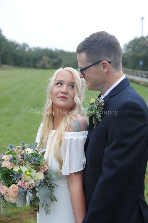 A bride gazes up into her grooms eyes as they stand closely outdoors