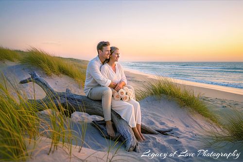 Bride and groom sitting on driftwood during a beach elopement in St. Augustine by Legacy of Love Photography.
