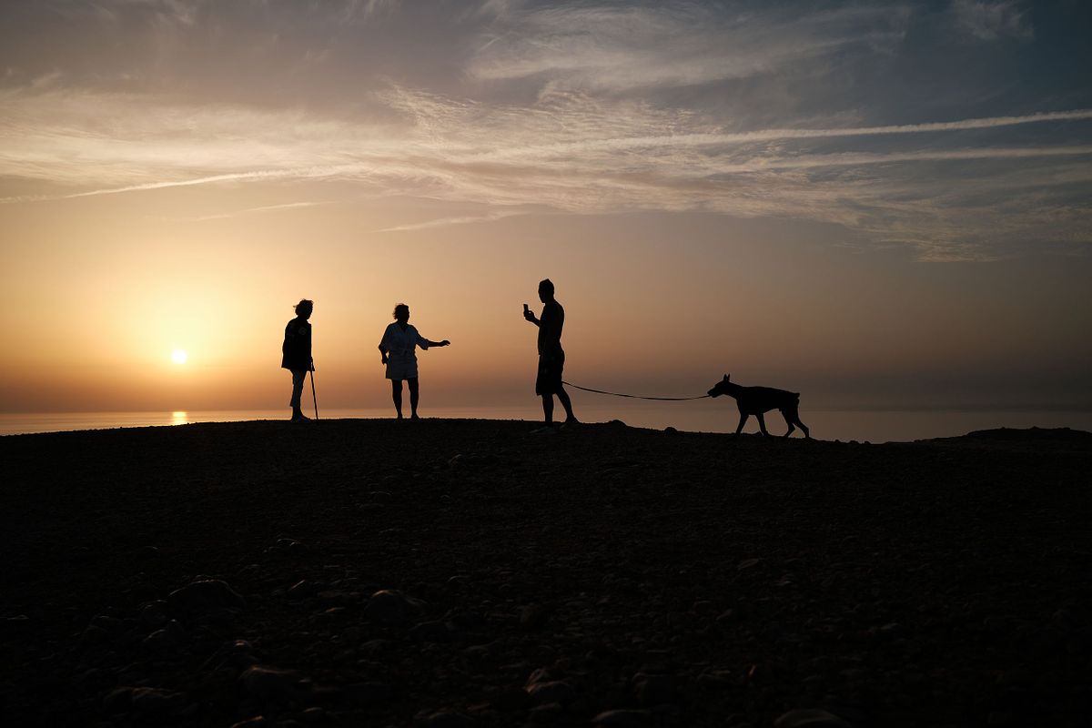 Silhouettes of people and a dog against a sunset backdrop, captured by photographer Sandeep Gajula