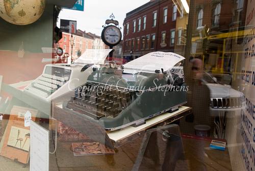 Vintage typewriters in a store window with a quintessential Portsmouth, New Hampshire Main Street scene in the background, highlighting the preservation of American