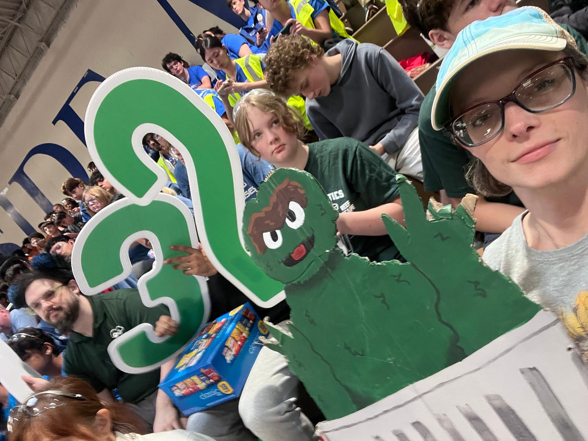 A picture of a mom supporting her daughter's robotics team from the bleachers.