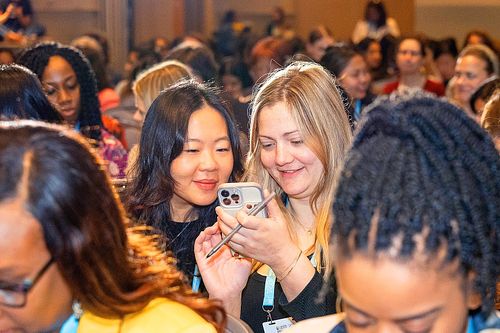 Two attendees share a joyful moment during a session break at the Grace Hopper Celebration 2024 in Philadelphia.