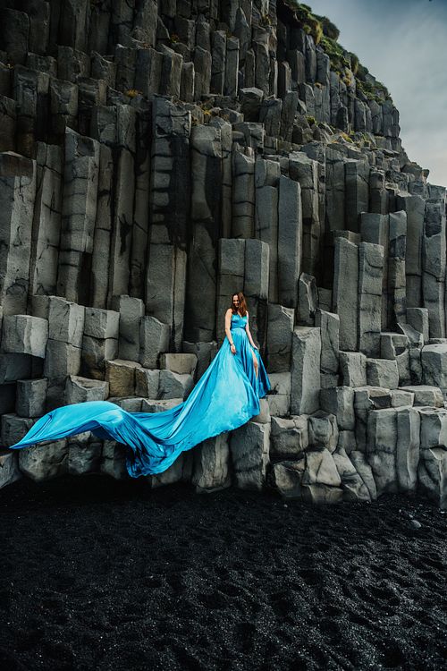Blue flowing flying dress portrait at basalt columns in south Iceland