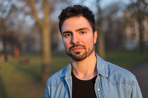 Headshot of Toni Gojanovic in a blue shirt standing in a park.