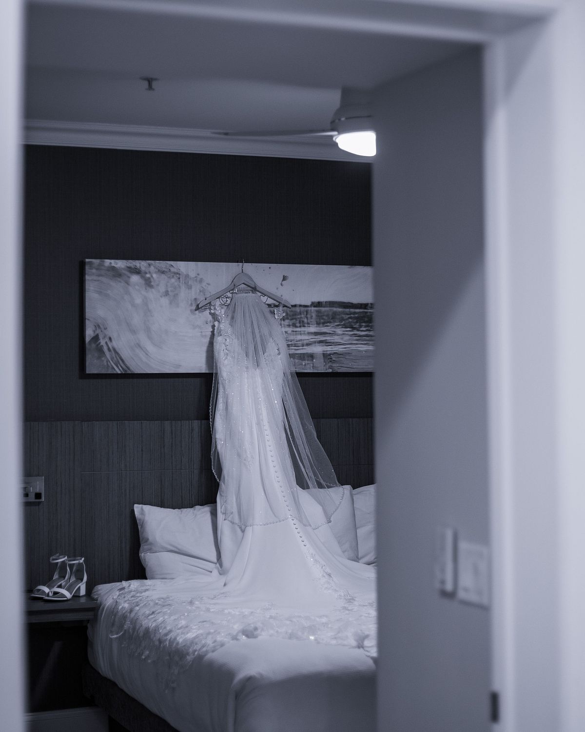 a peak at a wedding dress in the bedroom at hyatt in dewey beach, delaware, the photo is black and white