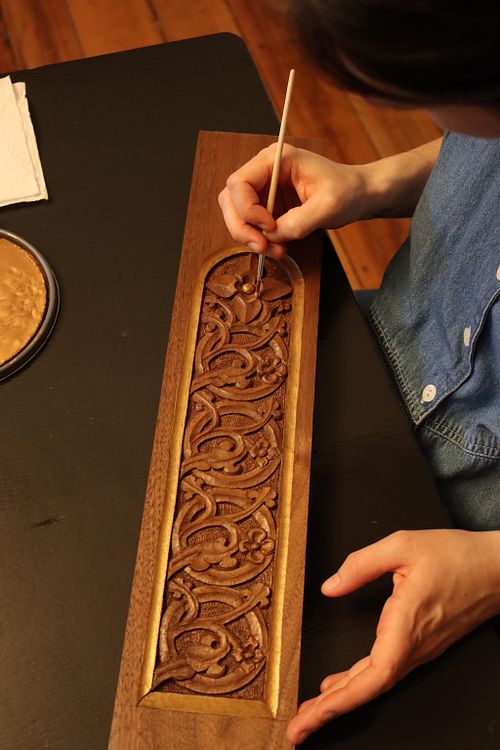 Kelly Baker paints fine details on the stem panel by hand