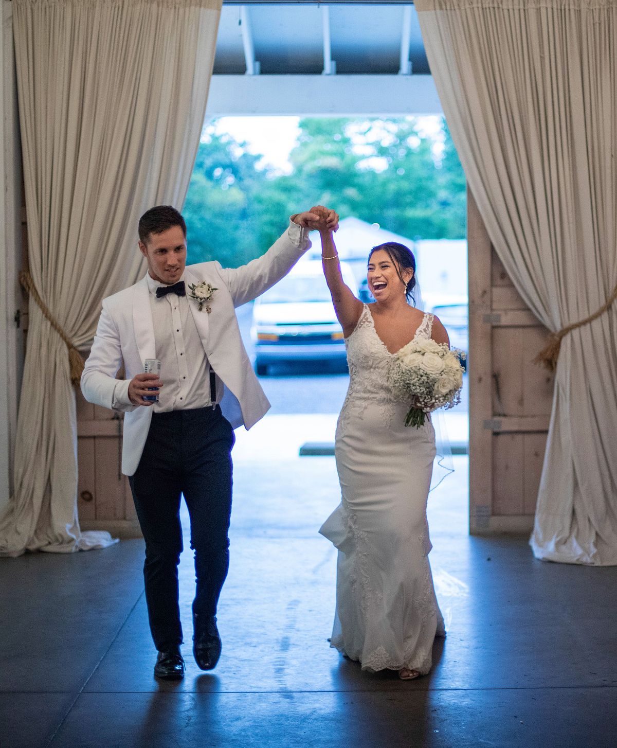 introduction of the bride and groom at kylan barn, the bride and groom are holding hands and raising them up.