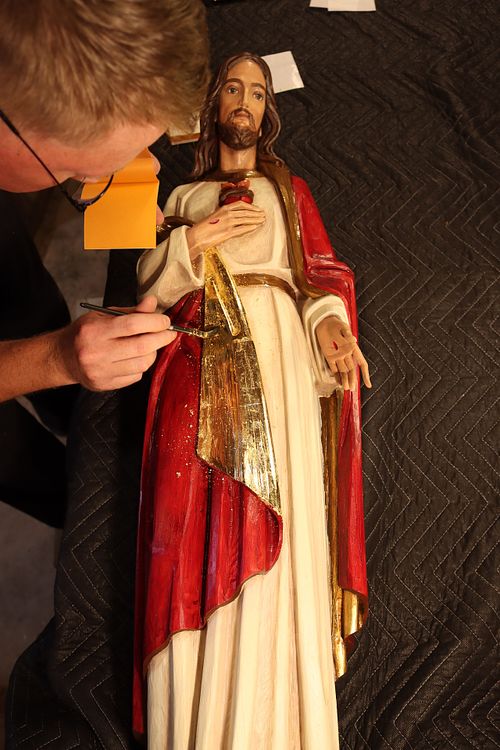 Wes Baker applying real gold leaf to the Sacred Heart of Jesus Statue