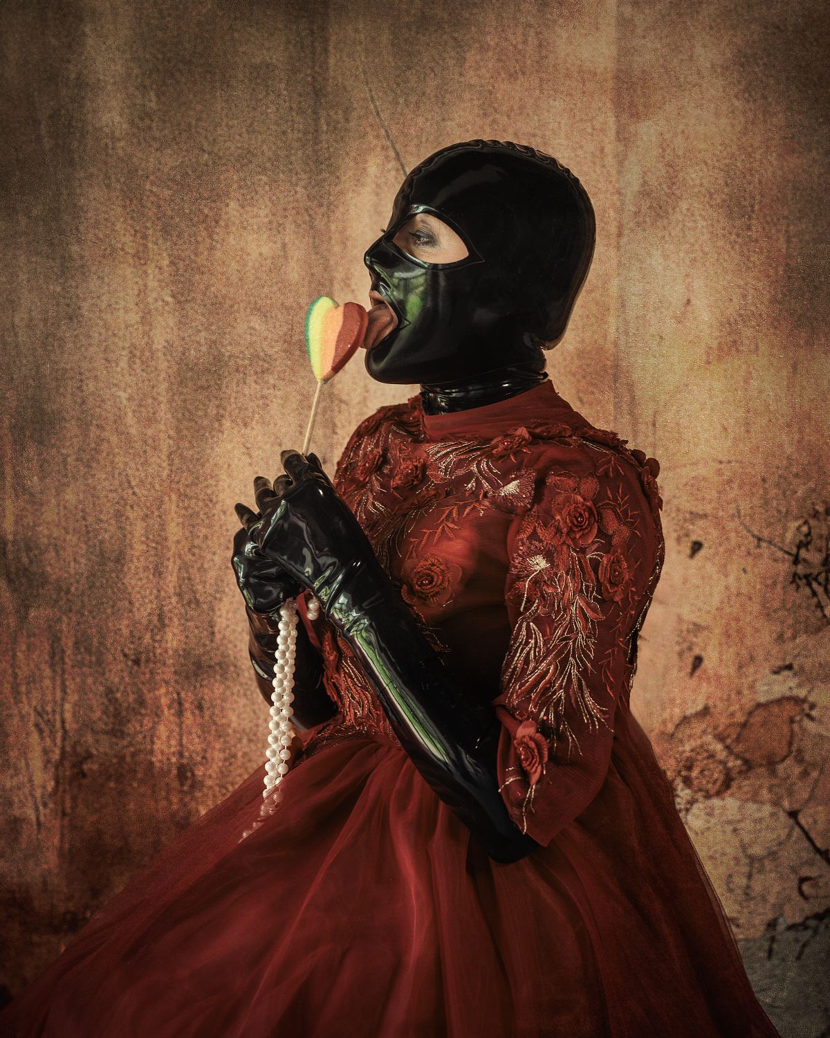 femme en robe rouge de princesse et tenue latex, léchant une sucette, regard provocateur, ambiance décalée et baroque, photographie fine art