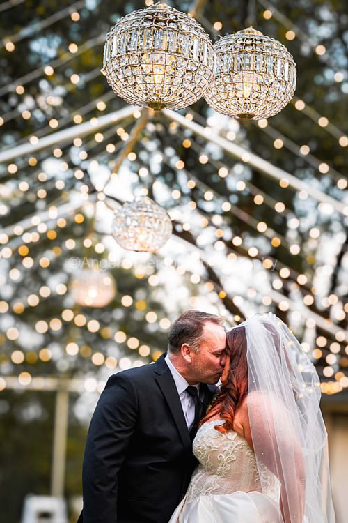 A bride and groom share a kiss under lights - South Dakota wedding photographer
