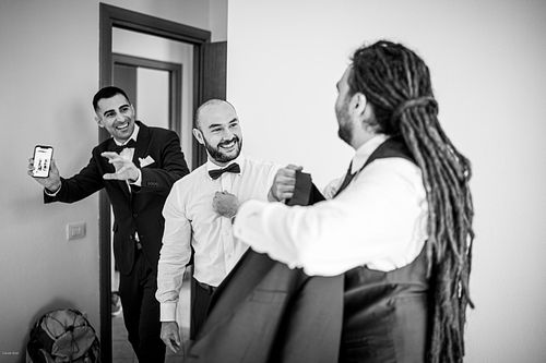 "bianco e nero invitati che raggiungono lo sposo che si veste"