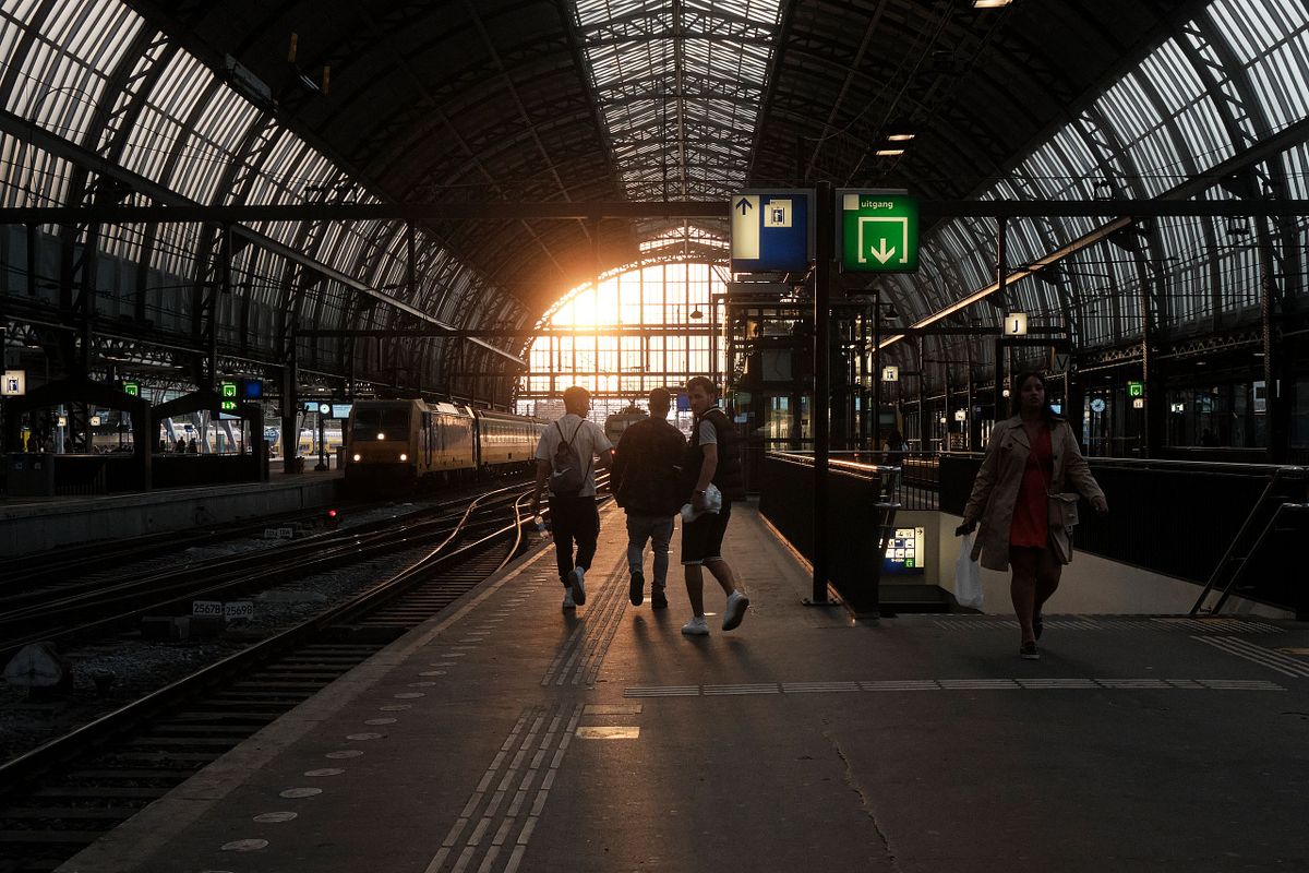 Travellers walking on the platform at Amsterdam Central Station during sunset, captured by photographer Sandeep Gajula