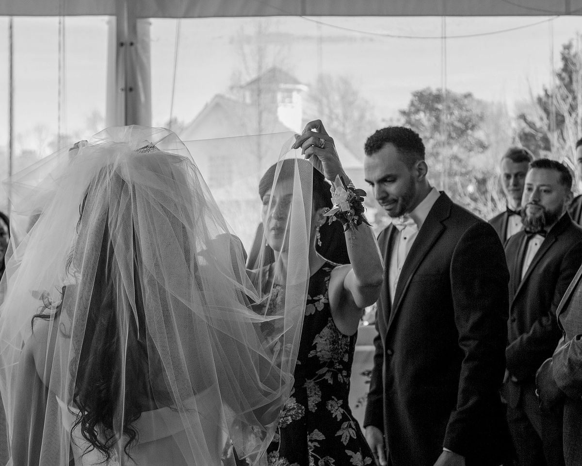 black and white photo of the mother of the bride removing the blusher veil before the ceremony on the porch at baywood weddings in milford, de