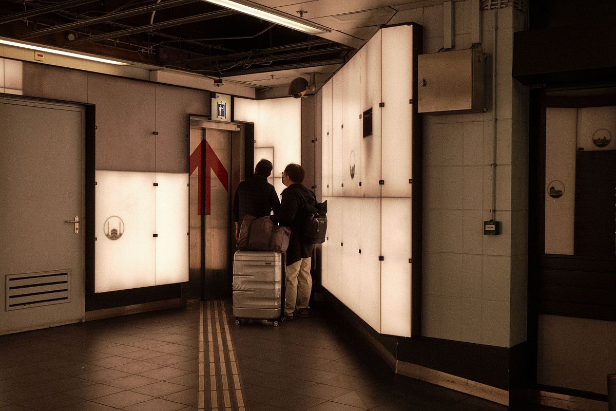 Two travelers with luggage at Amsterdam Central Station, captured by photographer Sandeep Gajula