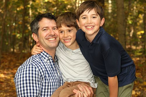 Dad hugs his two sons in the woods