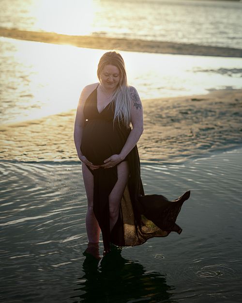 Expecting mother during golden hour in the lake with a flowing dress.
