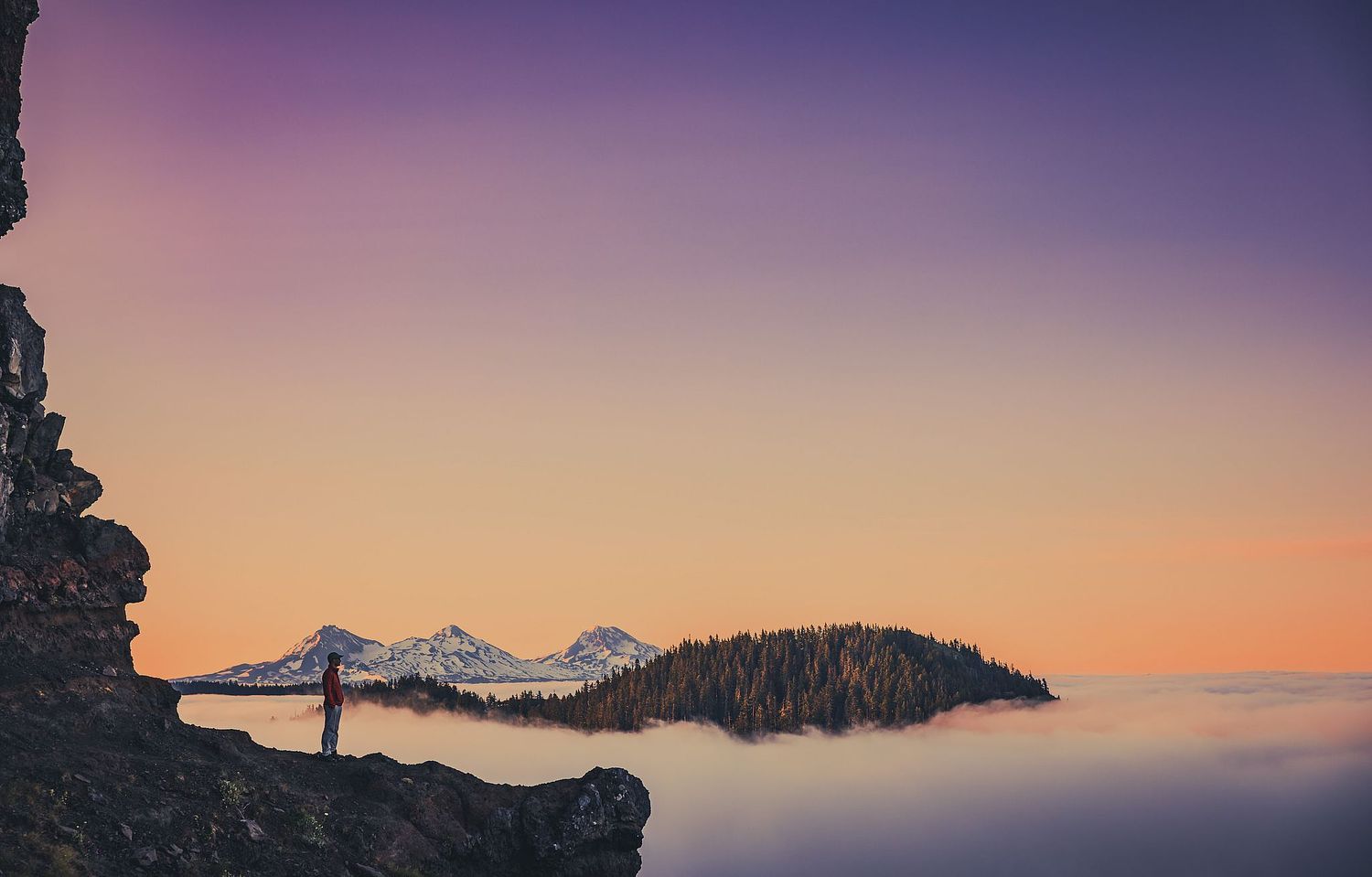 Sunrise over Three Sisters, colors spilling into sky.