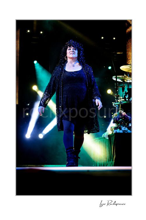 Vertical color image of Ann Wilson walking on stage during a Heart concert under bright blue and white stage lights