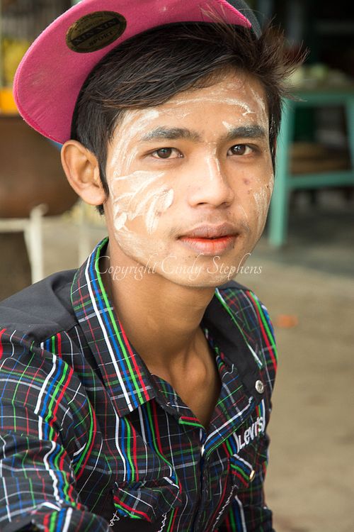 Young man in Myanmar with traditional Thanaka applied to his face, dressed in modern clothing, showcasing a blend of cultural identity