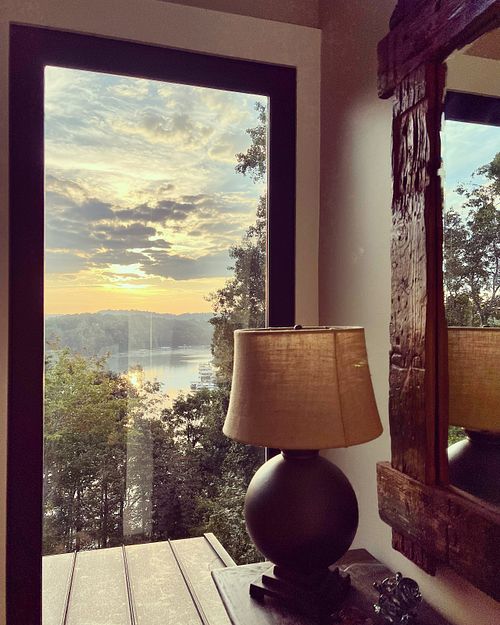 lamp on table in front of window that frames the view of the lake