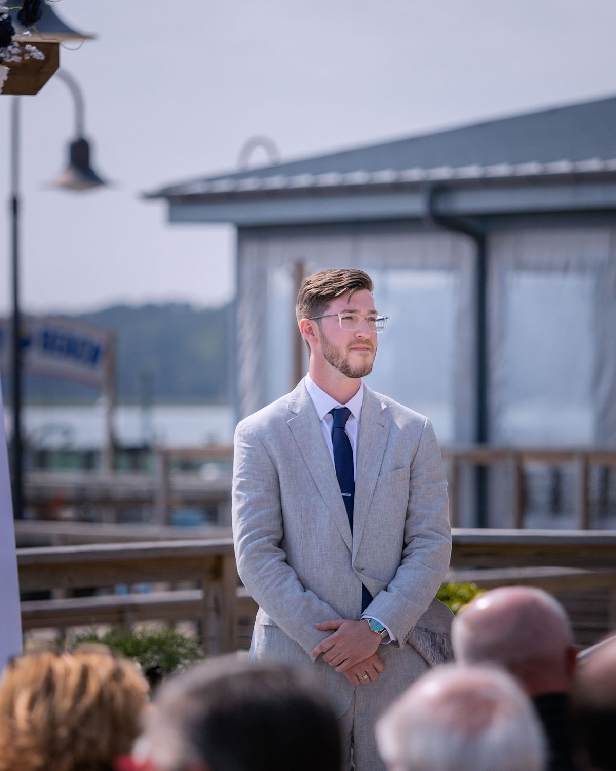 an emotional groom waiting for his bride on the terrace, his hands are crossed, the sun is shining