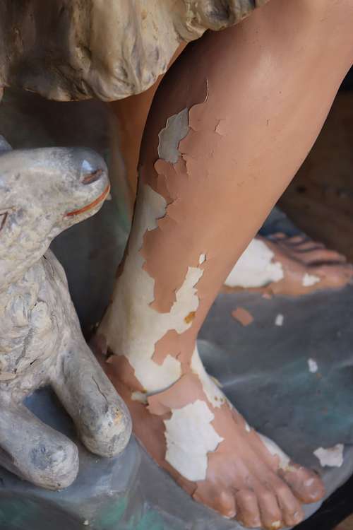 peeling paint from plaster statue foot in need of repair