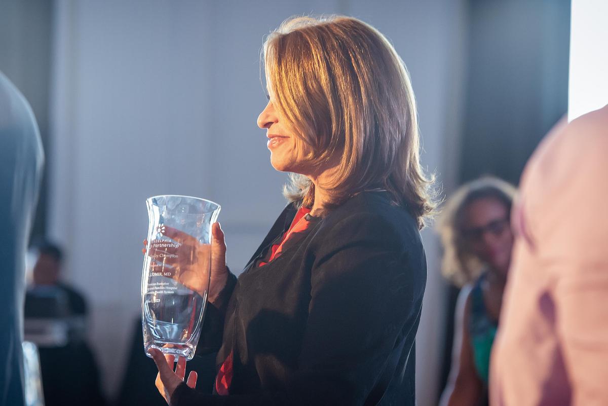 Corporate event photography capturing a woman holding a glass award during a recognition ceremony in Philadelphia, emphasizing leadership presence, professional achievement, and moments of shared celebration.