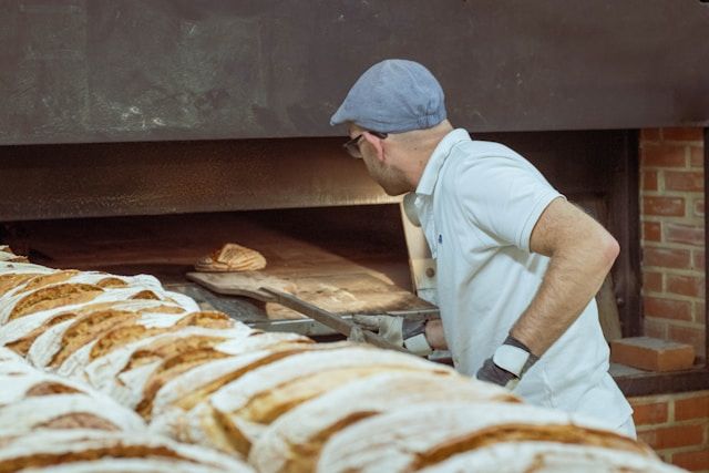 een bakker die een poloshirt en een pet draagt ​​in een bakkerij