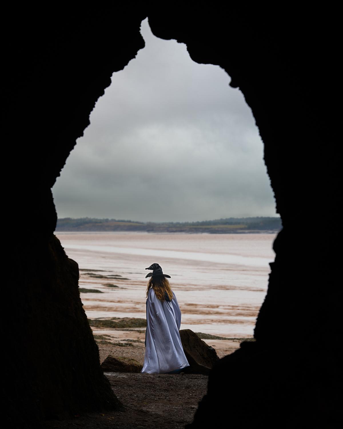 A witch looking out at the ocean framed by the Hopewell rock formations